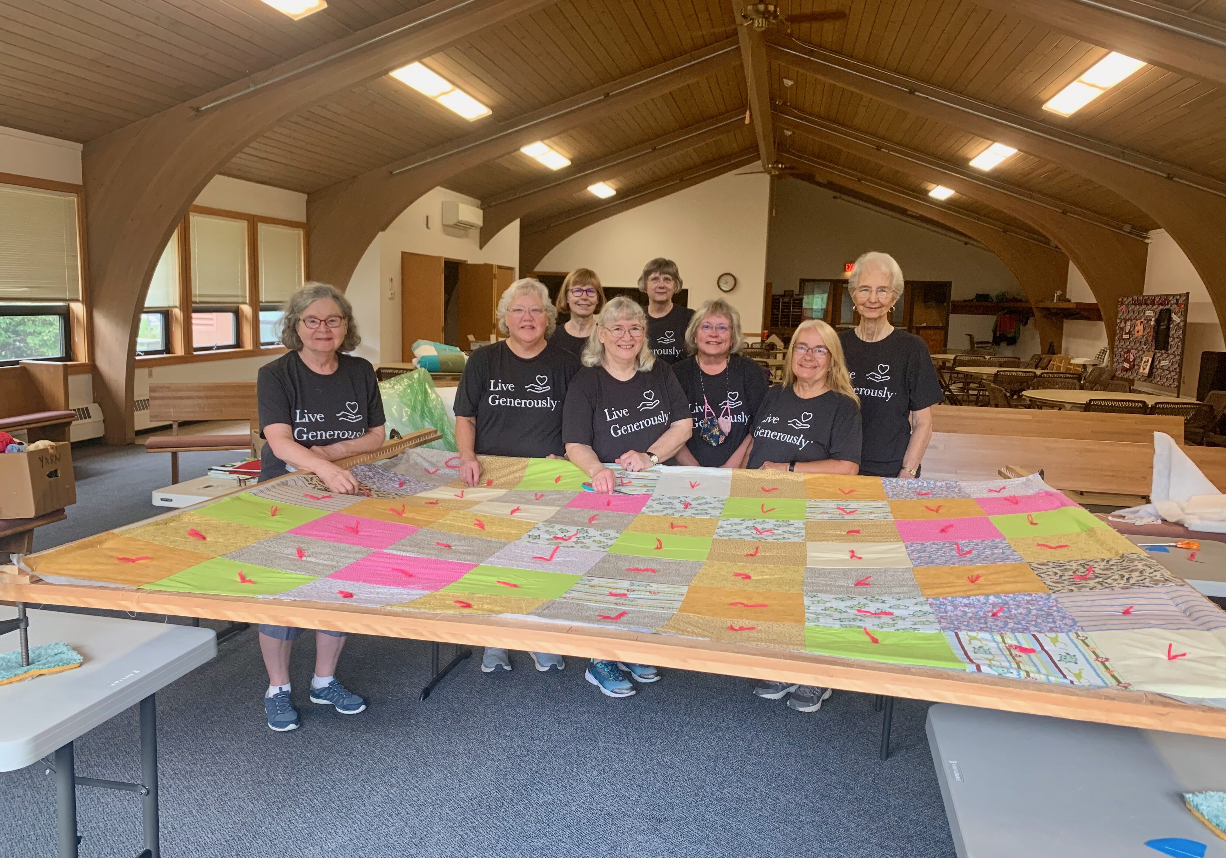 A group of people standing behind a quilt.